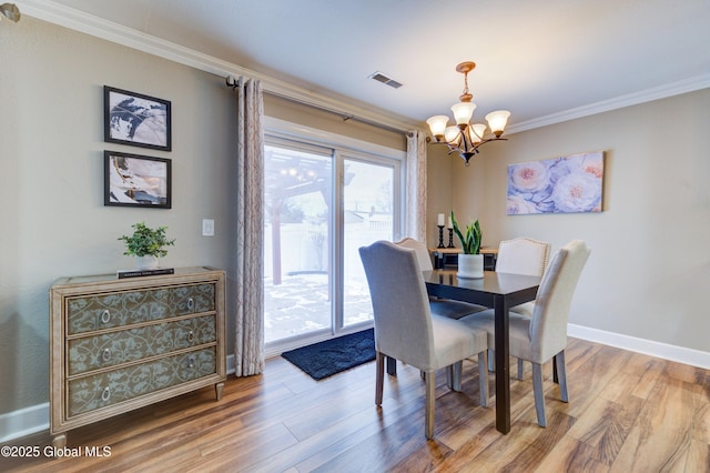 dining area featuring ornamental molding, an inviting chandelier, and hardwood / wood-style flooring