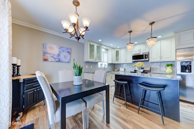 dining room with a chandelier, light wood-type flooring, and ornamental molding