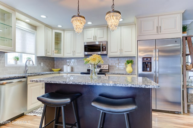 kitchen featuring a kitchen island, stainless steel appliances, light stone counters, and a chandelier