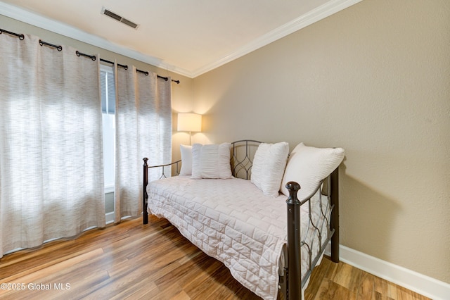 bedroom with ornamental molding and hardwood / wood-style floors