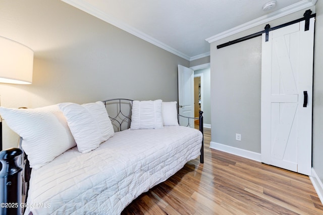 bedroom featuring ornamental molding, a barn door, and hardwood / wood-style flooring