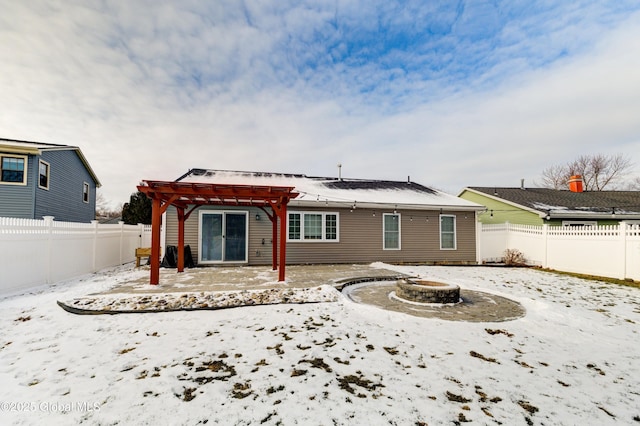 snow covered back of property with a pergola and an outdoor fire pit