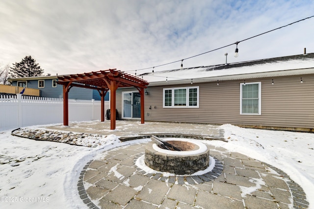 snow covered back of property with a pergola, an outdoor fire pit, and a patio area