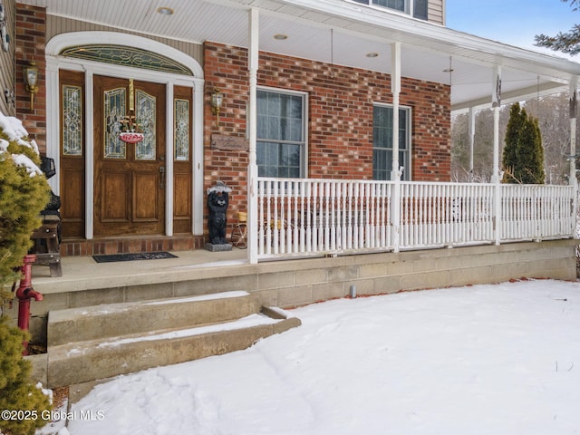 snow covered property entrance with covered porch