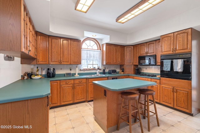 kitchen featuring a center island, sink, backsplash, a breakfast bar area, and black appliances