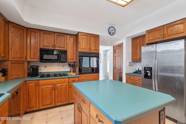 kitchen with backsplash, a kitchen island, black appliances, and light tile patterned floors