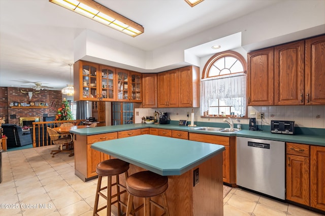 kitchen with ceiling fan, a breakfast bar, a kitchen island, and stainless steel dishwasher