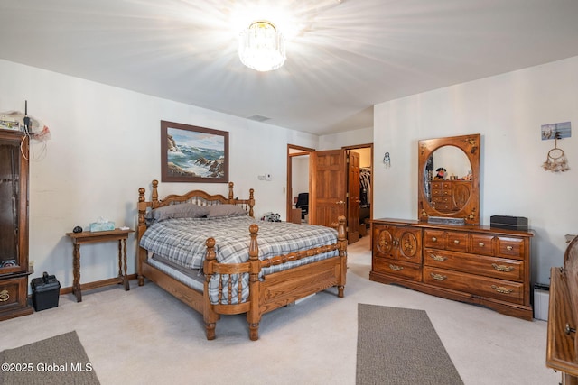 bedroom featuring a walk in closet, light colored carpet, and a closet