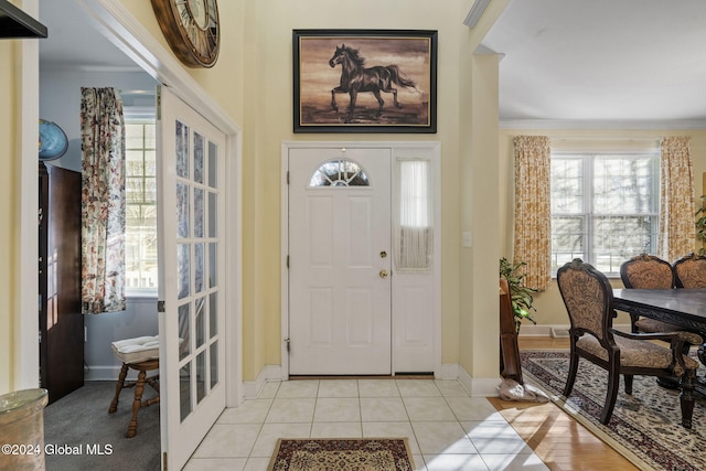 tiled foyer featuring ornamental molding and a wealth of natural light