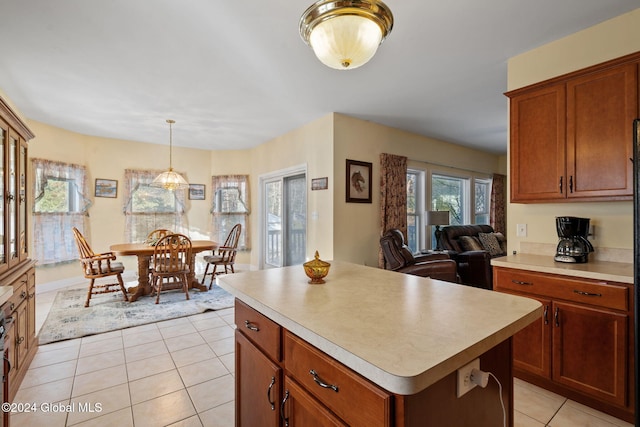 kitchen with a kitchen island, light tile patterned flooring, and pendant lighting