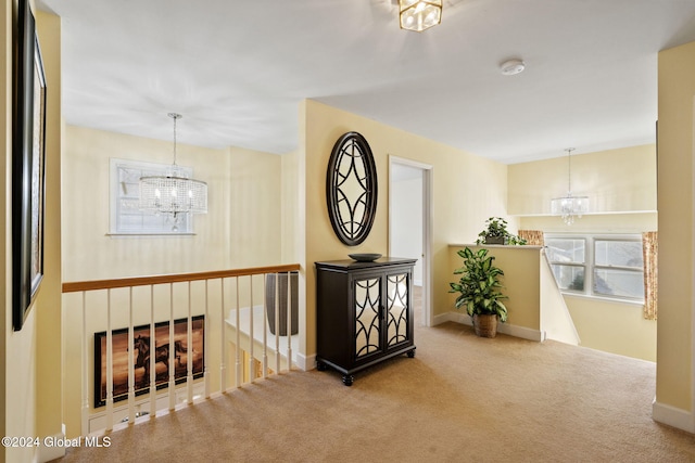 hall featuring an inviting chandelier and carpet flooring