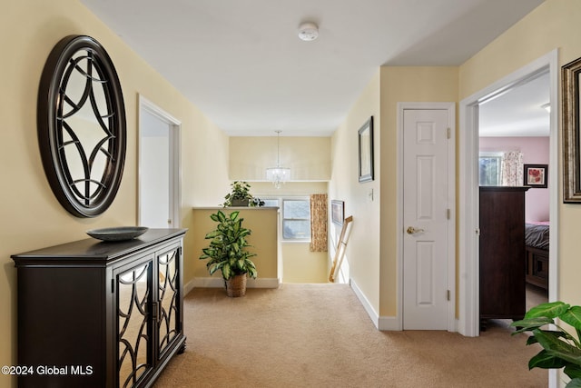 hall with a notable chandelier and light colored carpet