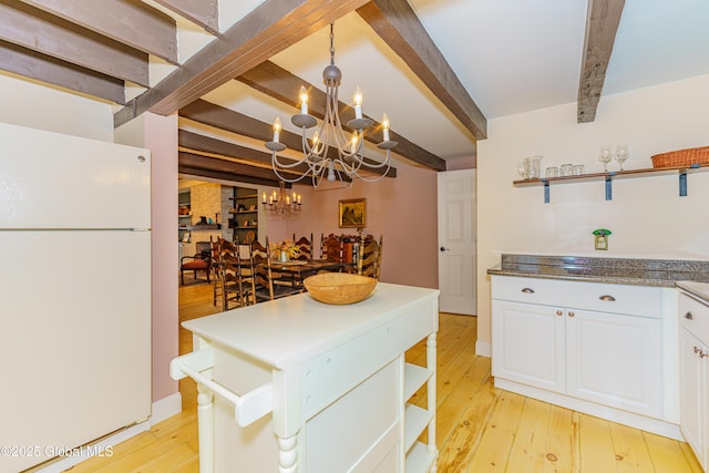 kitchen with light wood-type flooring, white refrigerator, decorative light fixtures, beamed ceiling, and white cabinets