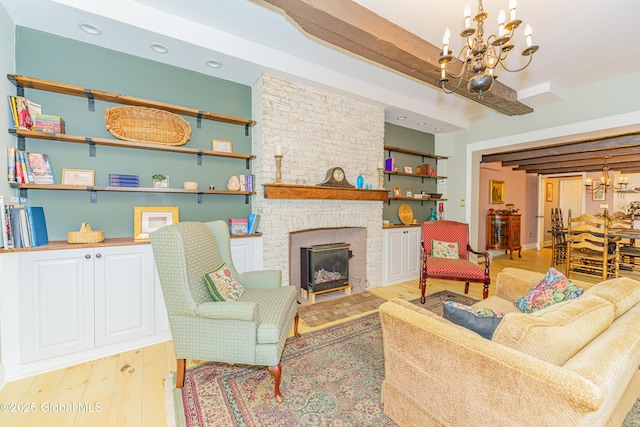 living room featuring a chandelier, beam ceiling, light hardwood / wood-style flooring, and a fireplace