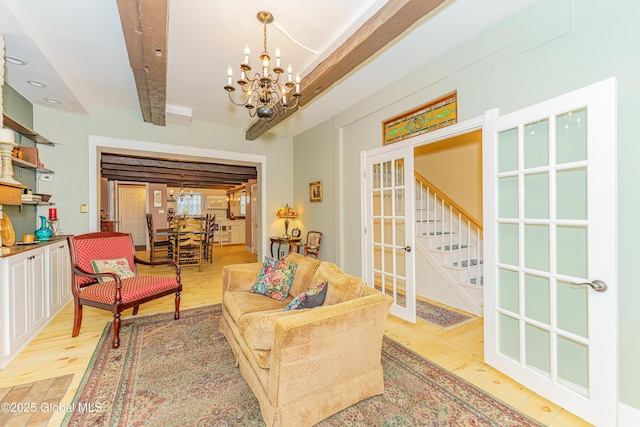 living room featuring beam ceiling, french doors, light hardwood / wood-style flooring, and a notable chandelier