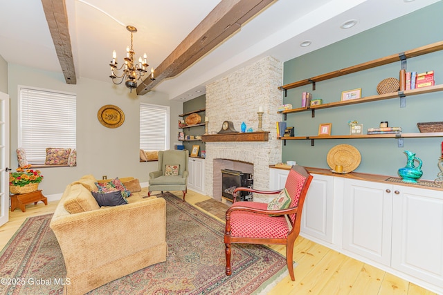 living room with a stone fireplace, light hardwood / wood-style flooring, beamed ceiling, and a notable chandelier