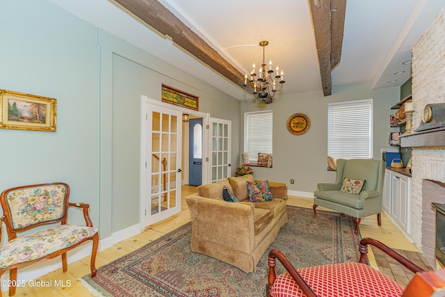 living room featuring french doors, light wood-type flooring, a brick fireplace, beam ceiling, and a chandelier