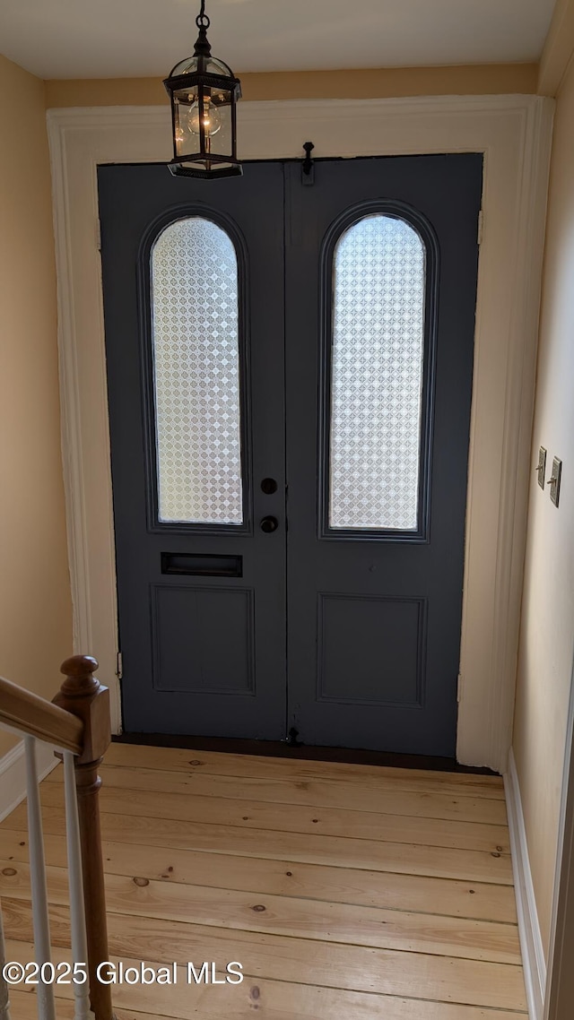 entrance foyer featuring a notable chandelier, french doors, and light hardwood / wood-style flooring