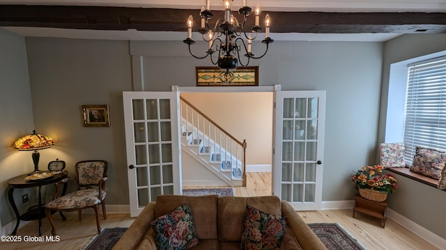 living room with beamed ceiling, light hardwood / wood-style floors, french doors, and a chandelier