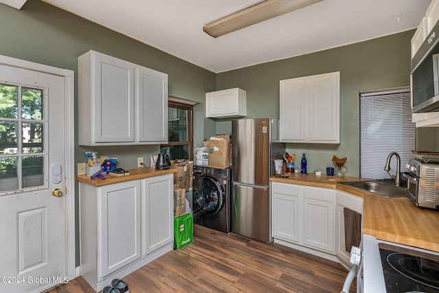 kitchen featuring wooden counters, washer / dryer, white cabinetry, and sink