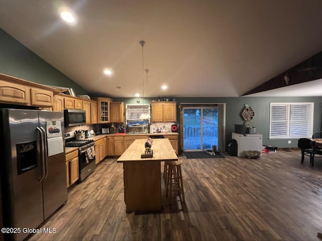 kitchen with a center island, hanging light fixtures, backsplash, vaulted ceiling, and appliances with stainless steel finishes