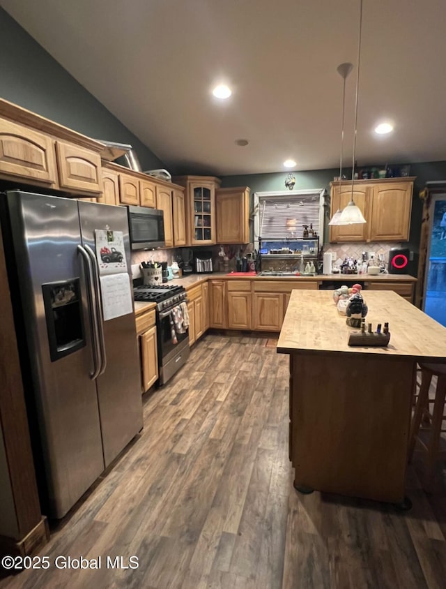 kitchen with decorative backsplash, appliances with stainless steel finishes, pendant lighting, dark hardwood / wood-style floors, and lofted ceiling