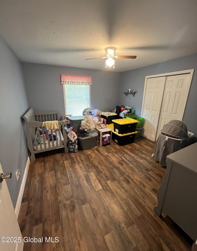 bedroom featuring dark hardwood / wood-style flooring, a closet, a nursery area, and ceiling fan