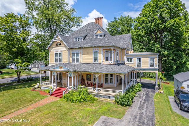 victorian-style house with covered porch, a front yard, and a carport