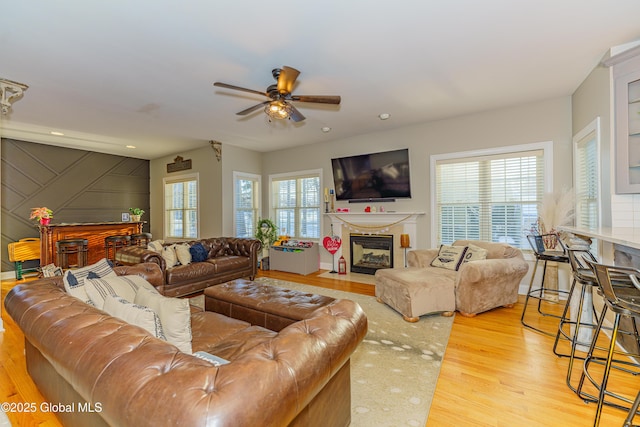living room with wood finished floors, ceiling fan, a fireplace with flush hearth, and recessed lighting