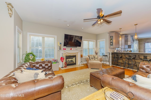 living room with wood finished floors, a ceiling fan, and a fireplace with flush hearth