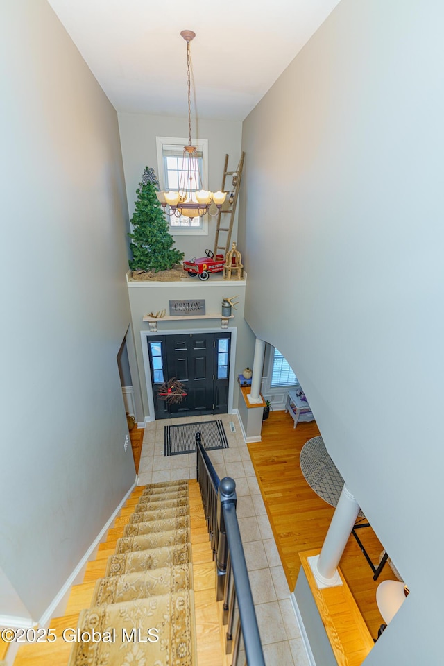 foyer entrance featuring a chandelier, baseboards, tile patterned flooring, and a high ceiling