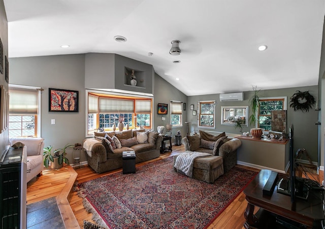 living room featuring ceiling fan, a wall mounted AC, hardwood / wood-style floors, and lofted ceiling