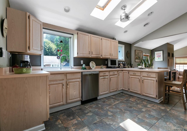 kitchen with light brown cabinets, kitchen peninsula, stainless steel dishwasher, and vaulted ceiling with skylight