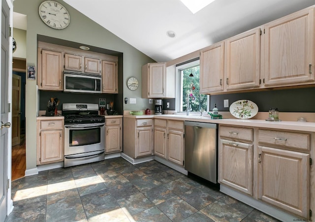 kitchen with stainless steel appliances, light brown cabinetry, and vaulted ceiling