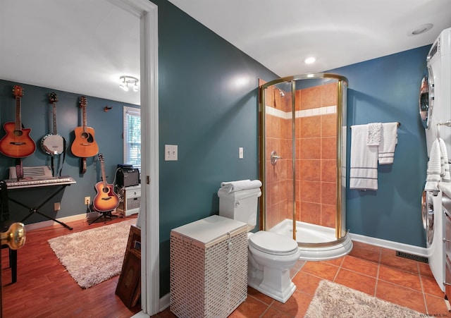 bathroom with toilet, a shower with door, and tile patterned flooring