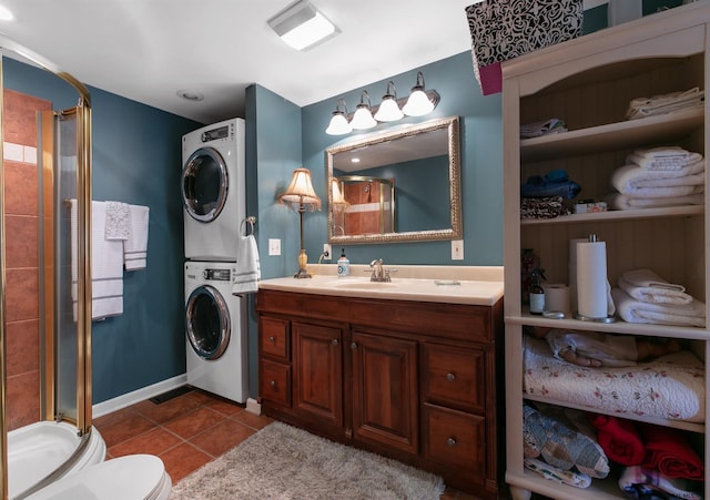 bathroom featuring toilet, an enclosed shower, tile patterned flooring, stacked washer / drying machine, and vanity