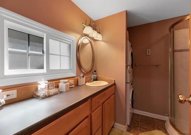 bathroom featuring a shower with door, tile patterned floors, stacked washer / drying machine, and vanity