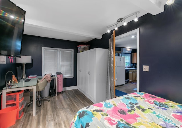 bedroom featuring beamed ceiling, white refrigerator, and wood-type flooring