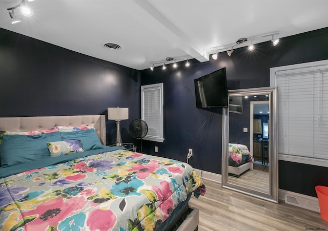 bedroom with light hardwood / wood-style flooring and beamed ceiling