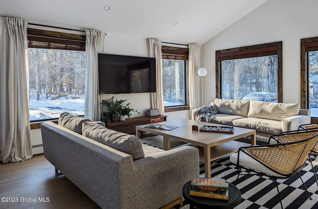 living room with plenty of natural light, wood-type flooring, baseboard heating, and vaulted ceiling