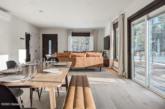 dining room featuring a wall mounted AC and light wood-type flooring