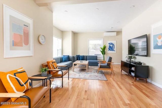 living room with a wall mounted AC and light hardwood / wood-style flooring