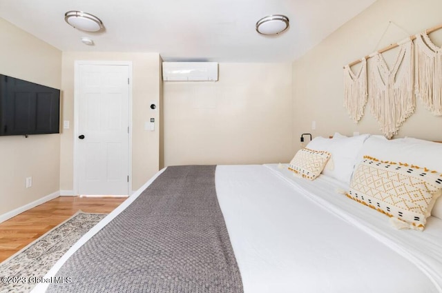 bedroom with a wall mounted air conditioner and hardwood / wood-style floors