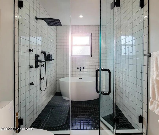 bathroom with tile patterned floors, shower with separate bathtub, and tile walls