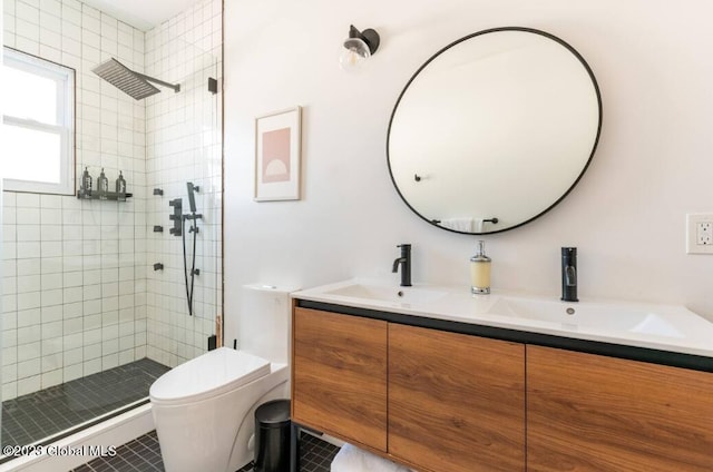 bathroom featuring toilet, tile patterned flooring, vanity, and tiled shower