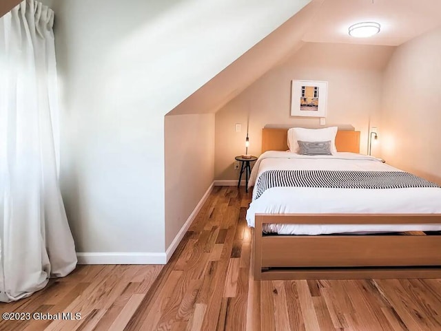 bedroom with light wood-type flooring and vaulted ceiling