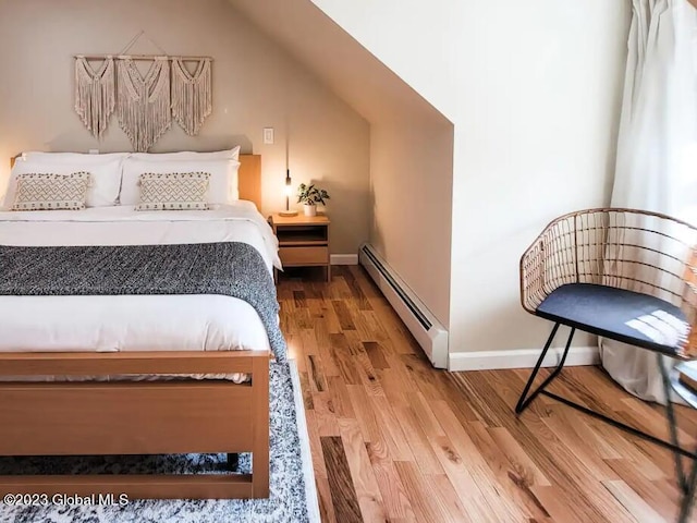 bedroom with hardwood / wood-style flooring, lofted ceiling, and a baseboard heating unit