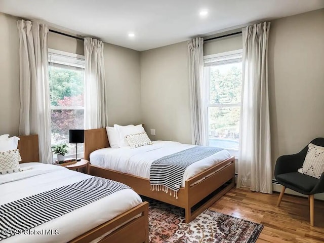 bedroom with light hardwood / wood-style floors and multiple windows