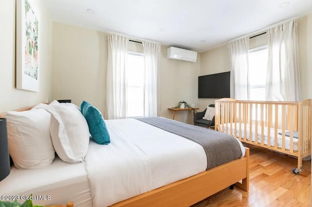 bedroom with an AC wall unit and hardwood / wood-style flooring