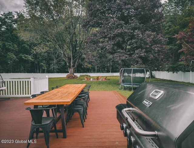 deck featuring a yard, a trampoline, and a grill